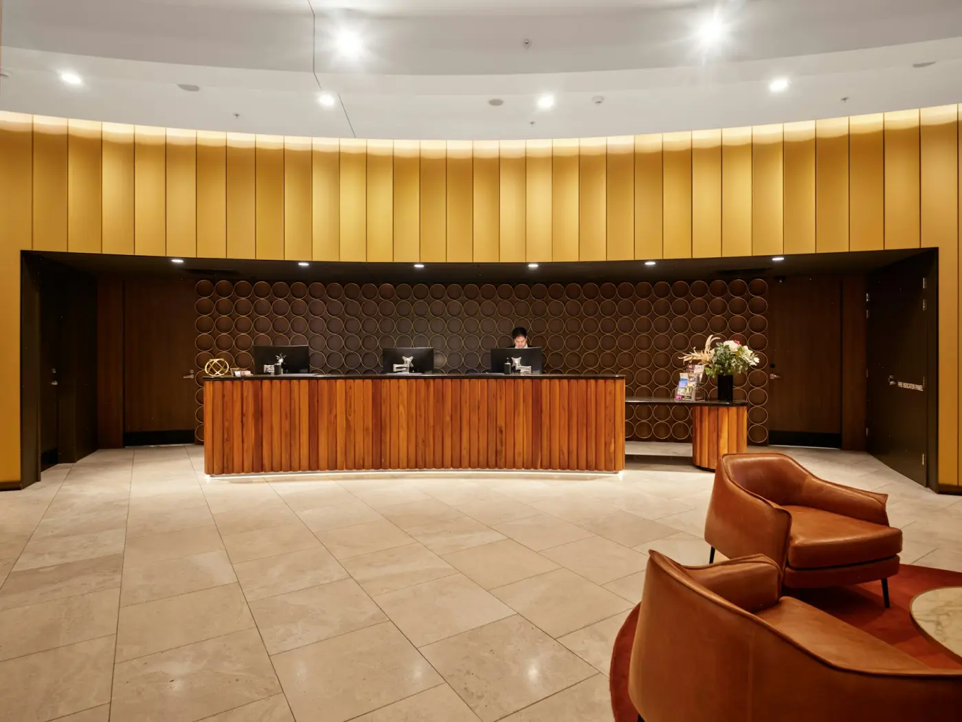 A warm hotel reception desk lit in the evening, with armchairs in the foreground